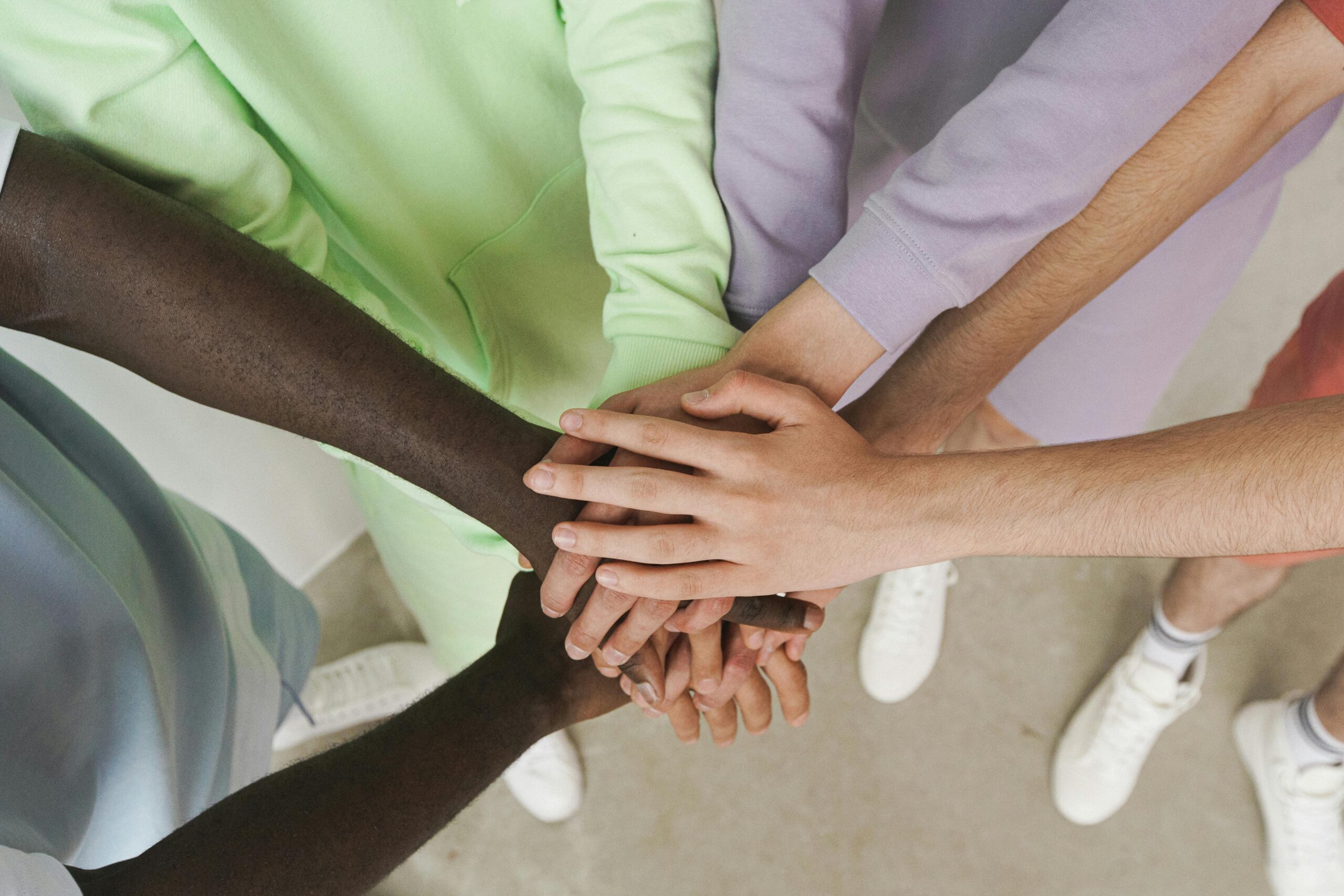 Top view of diverse hands stacked together, symbolizing unity and teamwork.